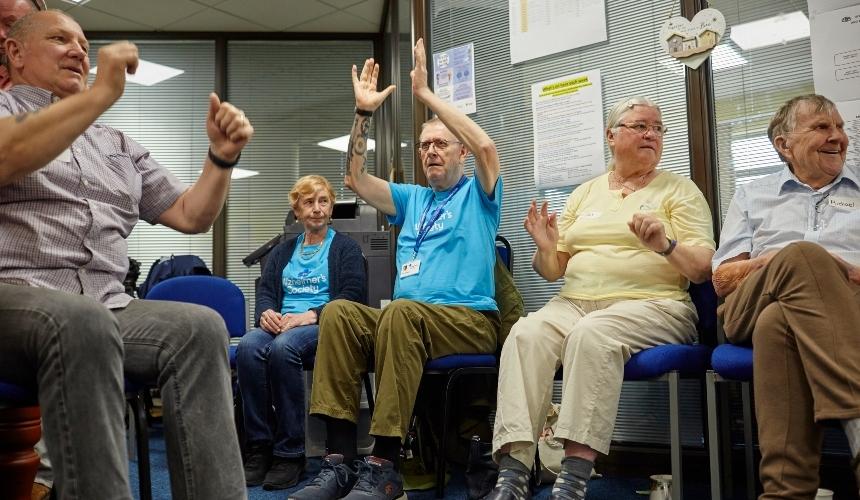 Image of Pete and other people engaged in physical activity. Pete is wearing a blue Alzheimer's Society t-shirt