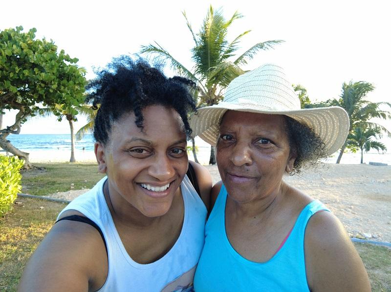 Armelle and Chantal stand together at the beach with trees in the background