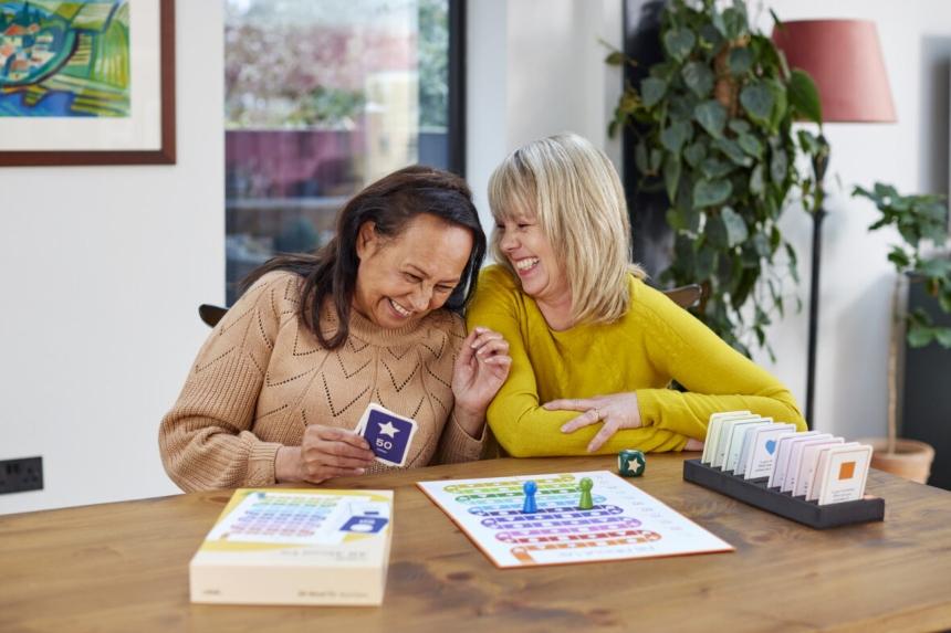 Two women smiling while playing the all about us game