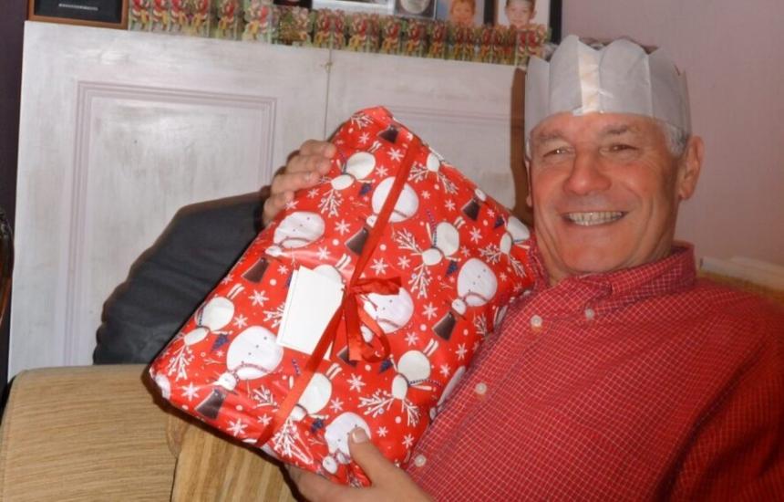 Adrian smiling while holding a wrapped gift