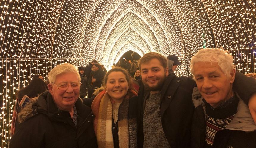 Adrian and his family stand arm in arm at Bath cathedral which is covered in white lights