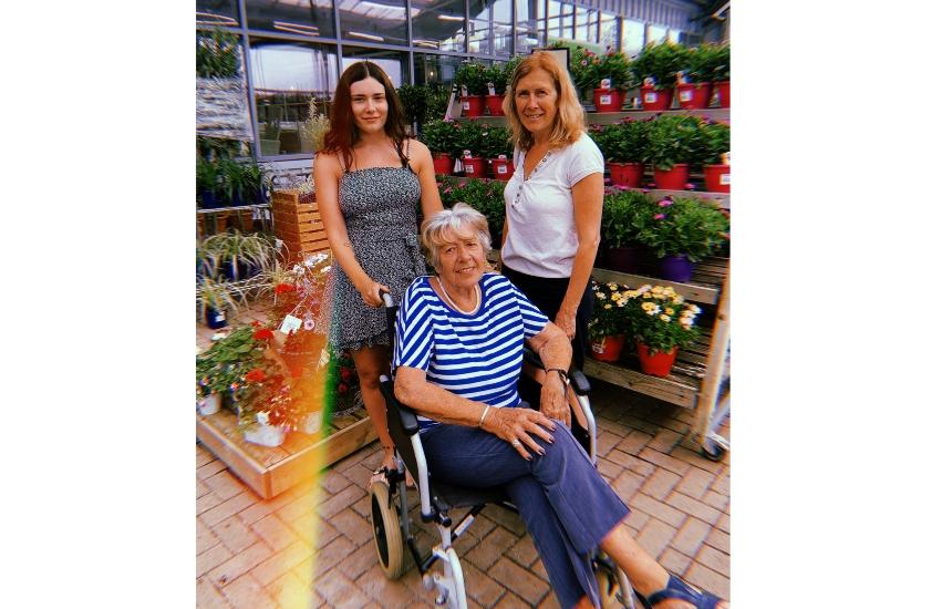 Grace and her mum stand with Nanna in between them in a wheelchair