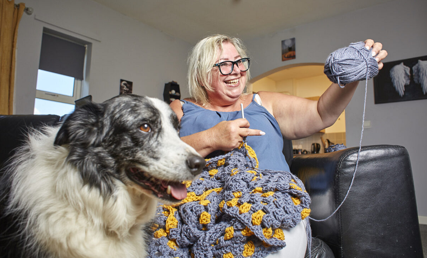 Anita knitting while sat with a dog
