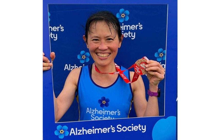 Ai Lyn after a run with her medal and an Alzheimer's Society cardboard cut out frame