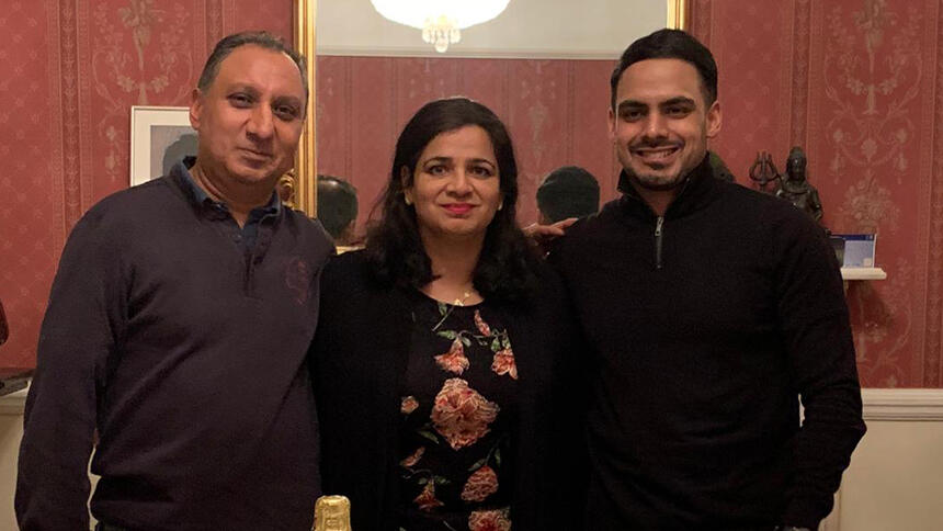 Amar is wearing a flowery dress and stood in between her husband Parminder and son