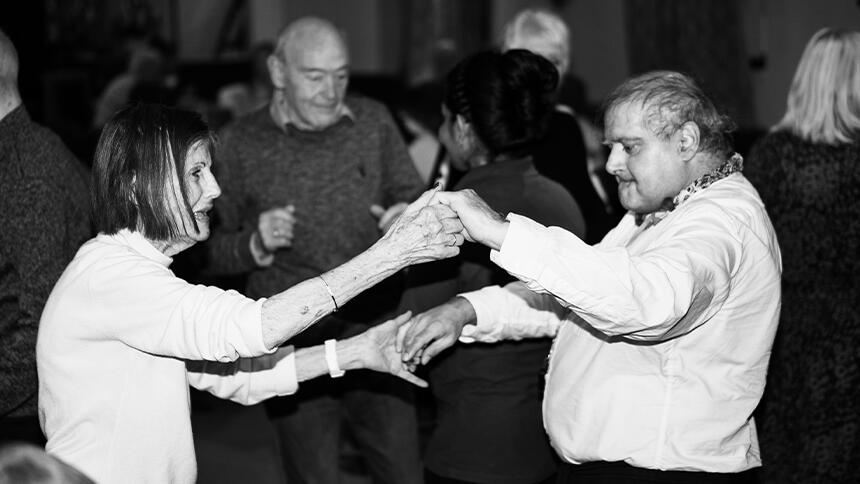 A black and white photo of a man and woman holding hands and dancing