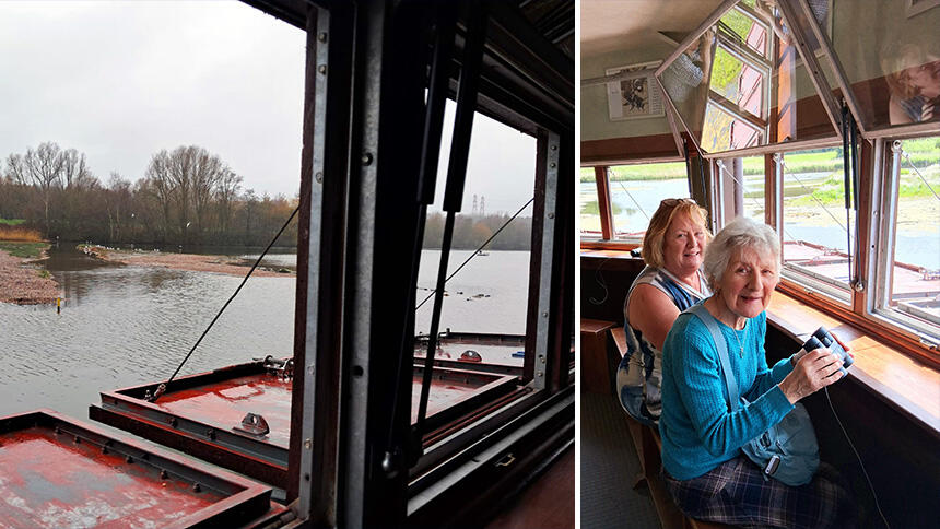 Looking out of the bird hide onto a lake, with two women looking out and holding binoculars