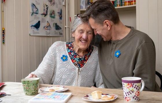 Smiling Kathy with her son Sean seated at the kitchen table