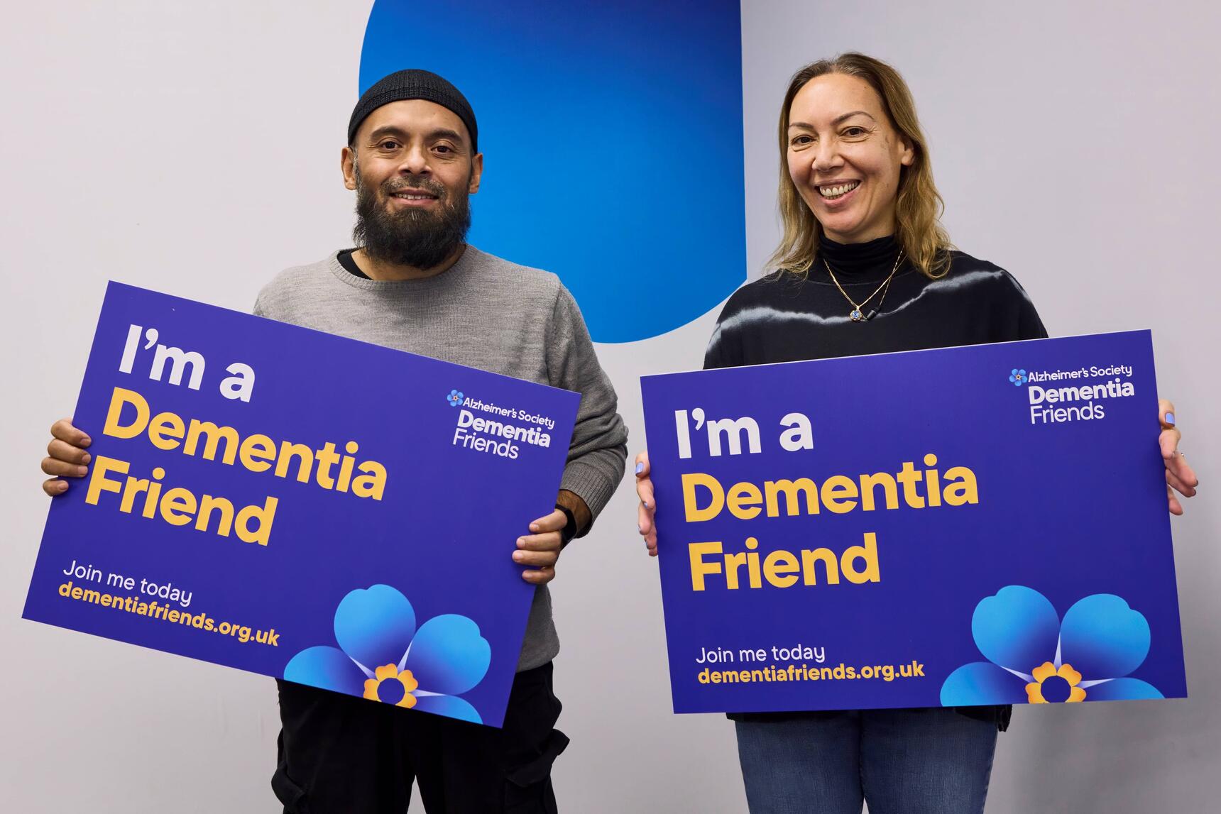 A man and woman holding blue signs that say I'm a Dementia Friend
