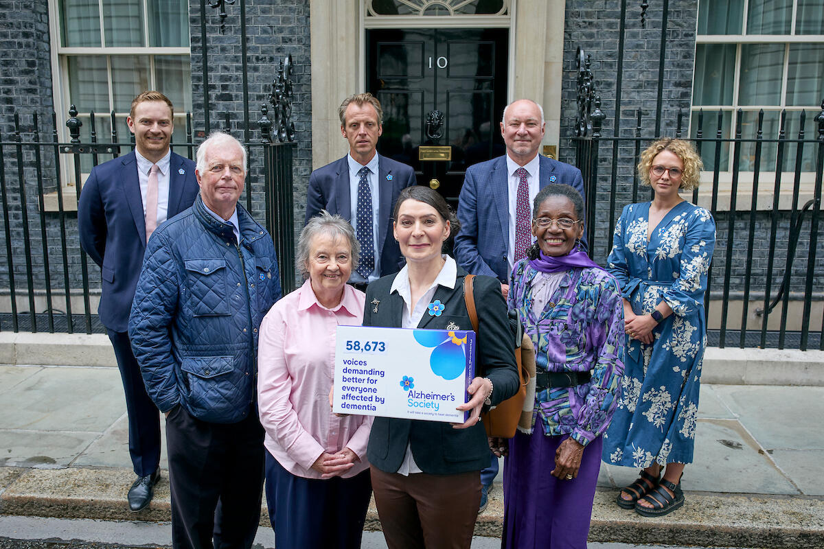 Eight people stand outside Downing Street with an open letter