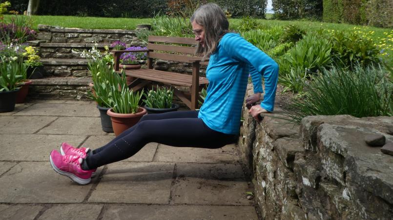 Jane demonstrating a tricep dip from a garden wall