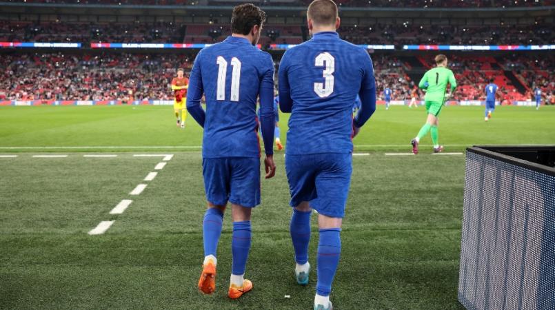 Two England players walking onto the pitch, with no names on the back of their shirts