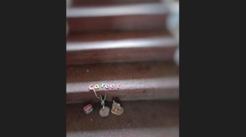 Colourful alphabet letters spelling 'career' are placed on a staircase. They are anchored from a post that is placed between a clock and a house figurine.