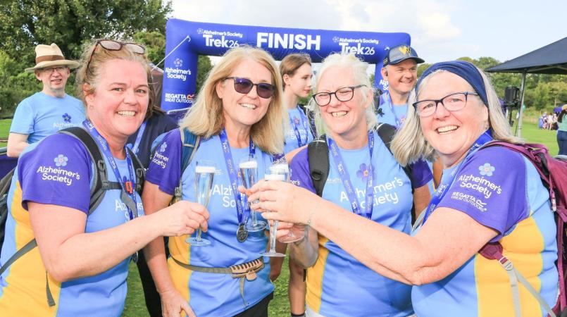 4 trekkers celebrating with fizz on the finish line
