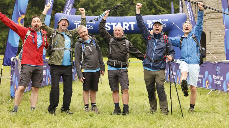 Six men cheering in front of an event start line.
