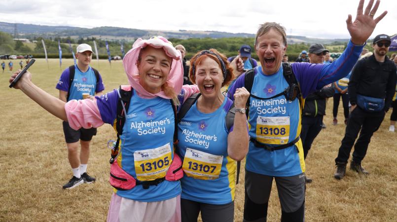 Woman in fancy dress smiling next to two happy trekkers.