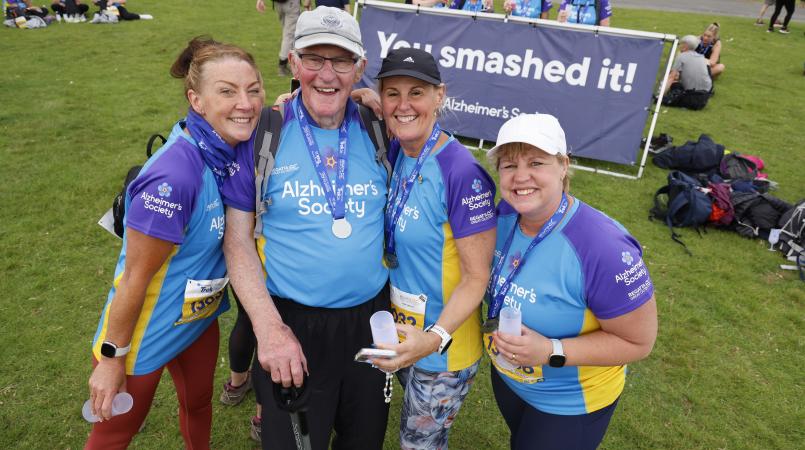Four people smiling with medals and glasses of prosecco.