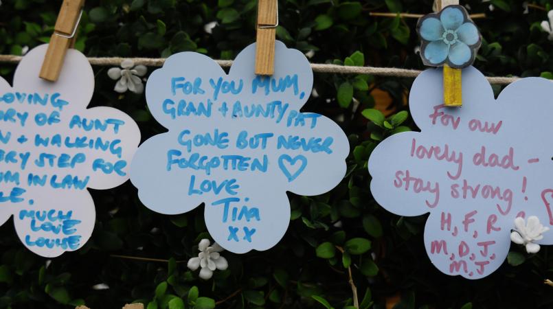 Forget me not paper flowers pegged on string with messages for loved ones.
