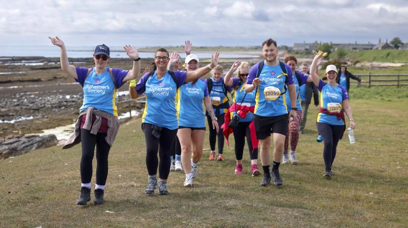 A group of people walking along a seaside cliff edge.