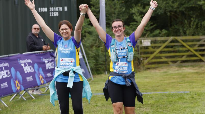 Couple walking to a finish line with their arms raised.