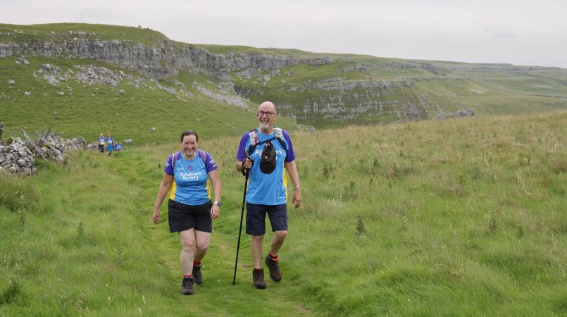 Two people walking on a hillside.
