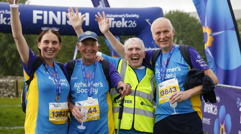 Four people cheering with a finish line in the background.