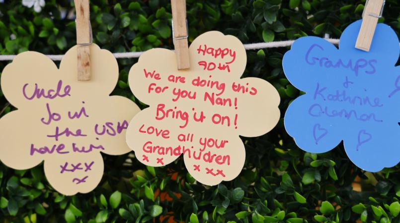 Forget me not paper flowers pegged on string with messages for loved ones.