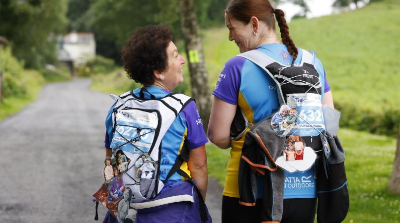 Two women walking away from the camera smiling.