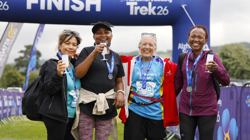 Group of people smiling in front of a finish line with medals and prosecco.