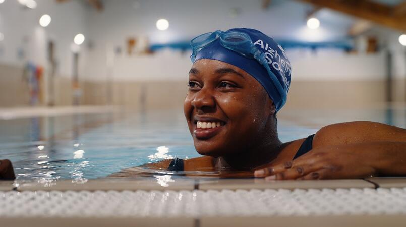 Adeola wearing an Alzheimer's Society branded swimming cap in a pool