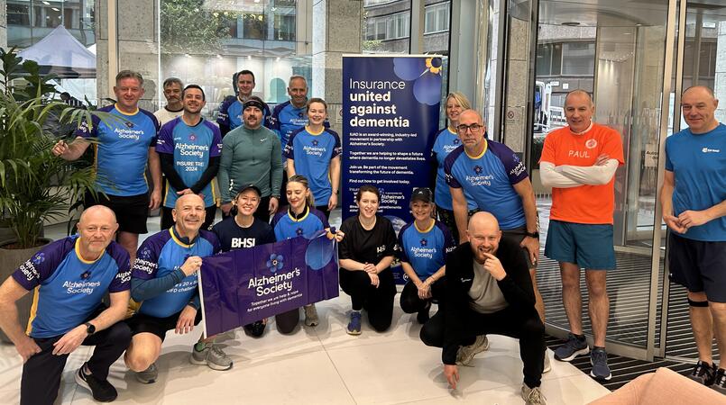A group of runners in Alzheimer's Society tops pose next to Alzheimer's Society's banners
