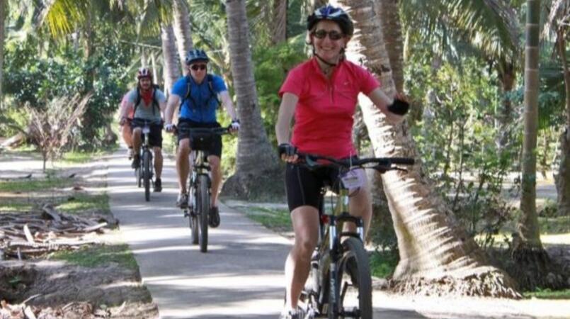 Three people riding bikes on a path