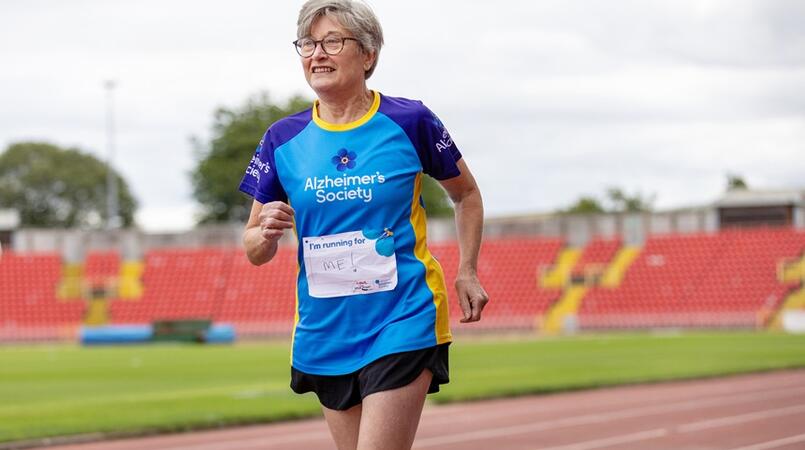 Woman running around an athletics track