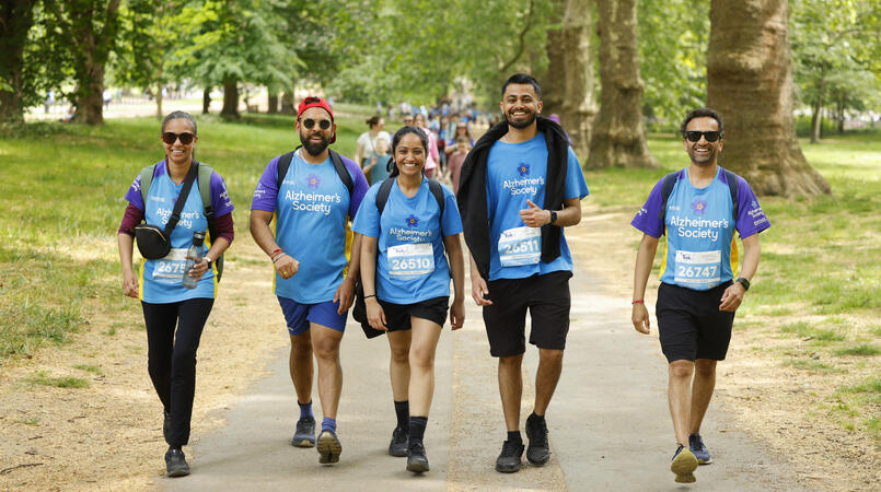 A group of people smiling walking on a path through trees