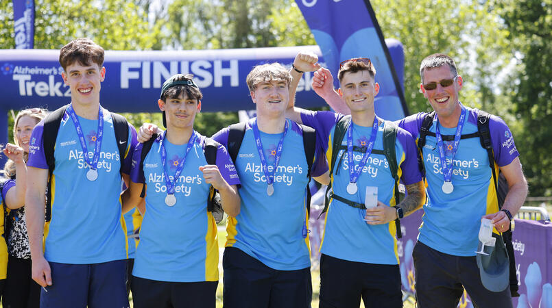 A group of people wearing medals at the finish line of a trek26 event.