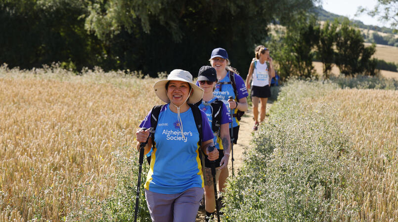 A group of people smiling as they walk through a field.