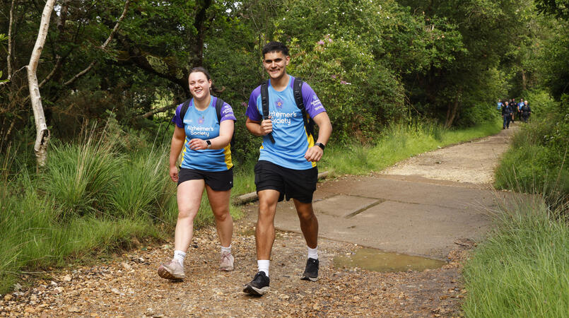 Two people walking along a path surrounded by trees