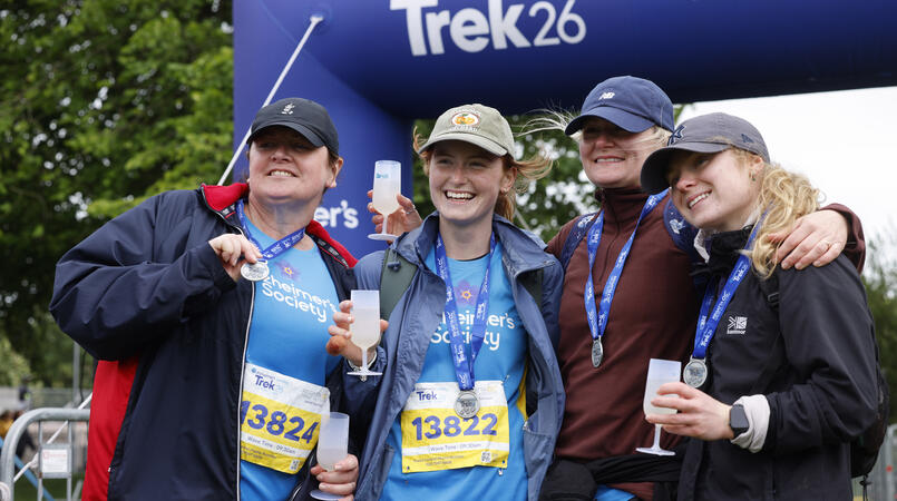 A group of people with medals standing at a trek26 finish line.