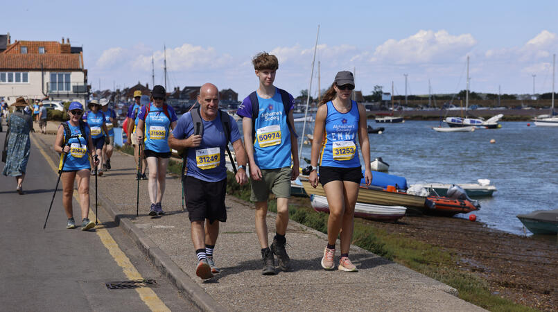 A group walking towards to the camera next to a harbour.
