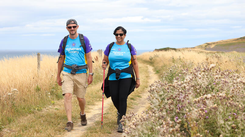 2 people walking towards the camera through a field.
