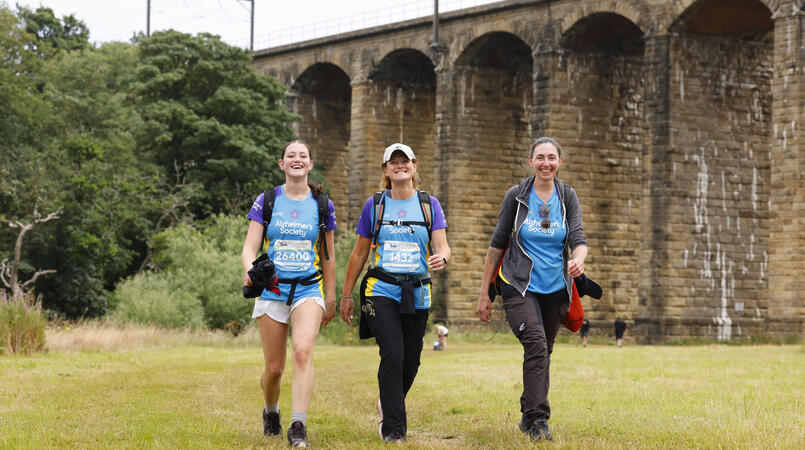 A group of three people smiling as they walk towards the camera.
