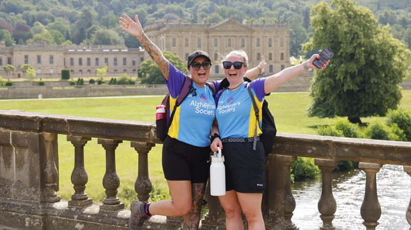 2 people smiling on a bridge wearing Alzheimer's Society tops.