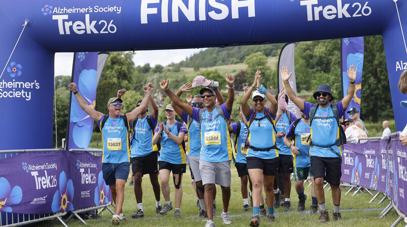 A group of people smiling as they cross a trek26 finish line.