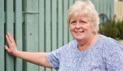 Chris Maddocks smiling and standing with an arm leaning on a wall