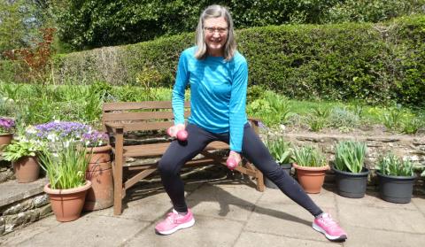 Jane demonstrating a side lunge while holding weights