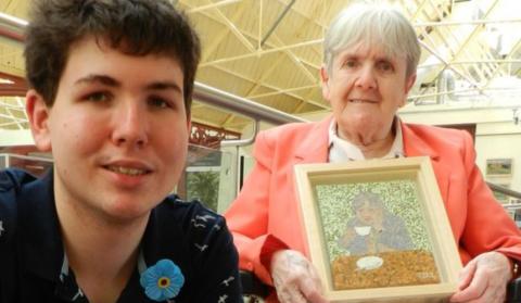 James with his grandmother Joan who holds up his artwork