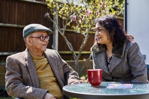 A man and a woman talking in the garden over a hot drink
