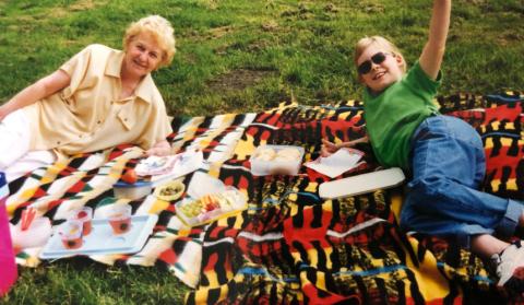 Hannah with her Nanny lying on picnic blankets, waving and smiling