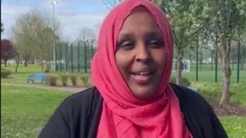 Samia Egeh stands in a park wearing a hot pink headscarf and is in conversation