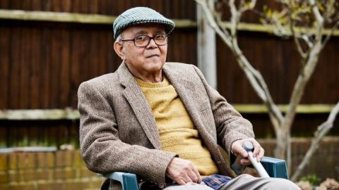 An older man sitting in a chair in his garden
